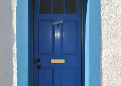 A blue front door. Number 63 above the lintel.
