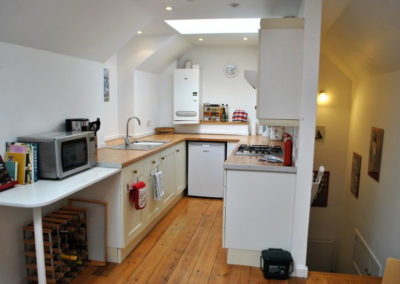 Galley kitchen, showing microwave on a counter on the left and stairs down on the right