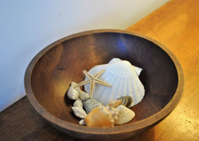 A wooden bowl filled with shells and a starfish