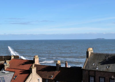 View of the sea over rooftops. An island can be seen on the horizon