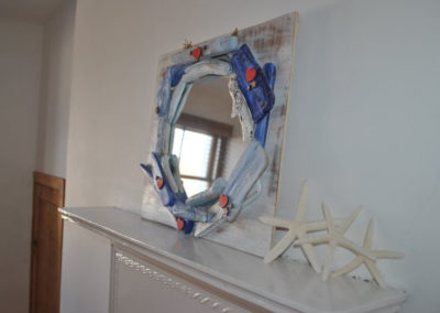 A mirror made with driftwood sits on the mantelpiece beside three starfish.