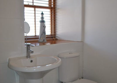 Sink and toilet in front of a window with a lighthouse model