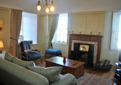 View of lounge showing three windows, sofa, chair and fireplace