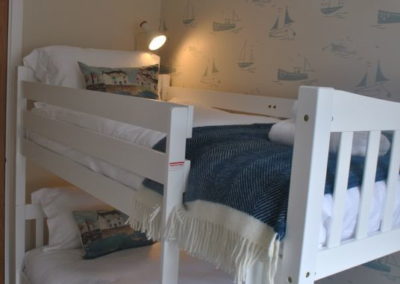 White bunk beds. Room has ships on the wallpaper.