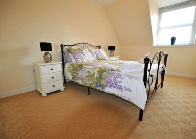 Metal frame double bed in spacious, light room with window and sloping ceiling