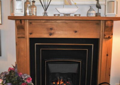 Gas fire with wooden surround and mantelpiece.