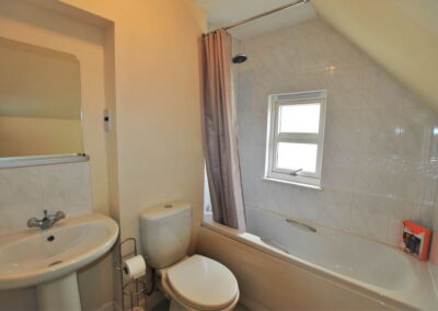 Bath beneath a sloping ceiling. Small window in wall above bath.