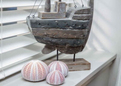 Sea urchins sit on a window ledge next to a model of a ship