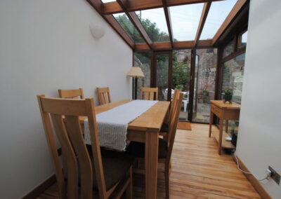 Dining table set for six beneath a glass conservatory roof