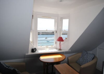 View of harbour from window, in front of which is a round table and chair