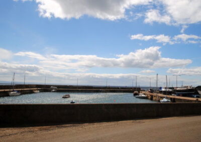 View of boats in harbour beneath a blue sky with clouds