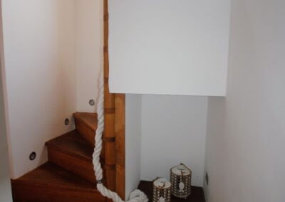 Rope handrail curving up a wooden staircase