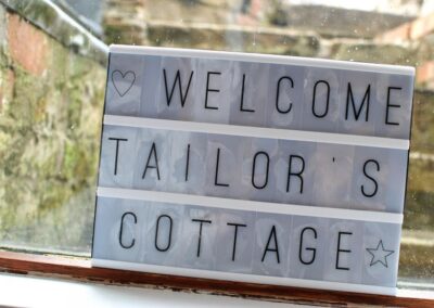 Illuminated sign reading Welcome Tailor's Cottage