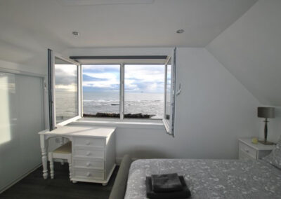 Double windows open above dressing table to sea views beyond