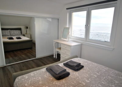 Opposite the bed is a built-in wardrobe with a mirrored door in the centre