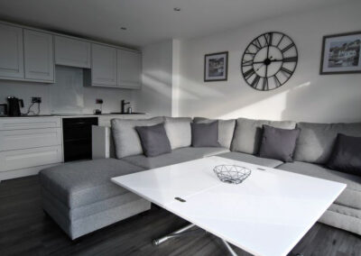 White coffee table in front of grey corner sofa with cushions