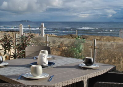 Table on patio with coffee cups and coffee jug, looking out towards the Isle of May on the horizon.