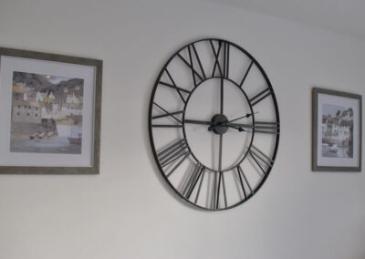 Large clock with Roman numerals between two paintings