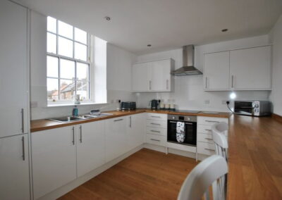 Modern fitted kitchen with white units and wooden worktops