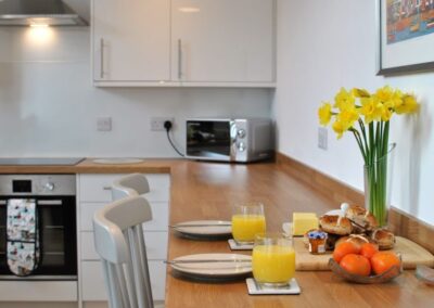 Breakfast bar against the wall, set for two places with a vase of daffodils