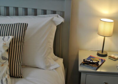 Pillows on bed next to bedside table with bedside lamp
