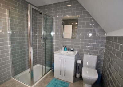Grey tiled room with walk-in shower and white fittings
