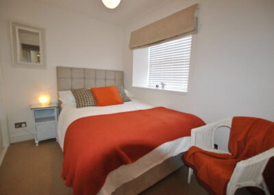 Single bed with deep orange and white linen