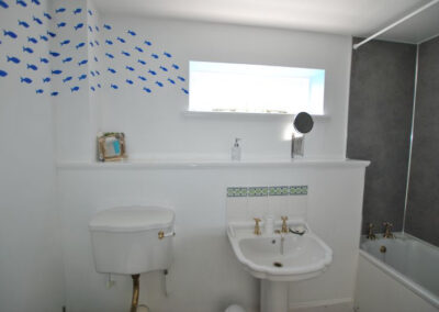 White bathroom with blue fishes on wall swimming towards the window