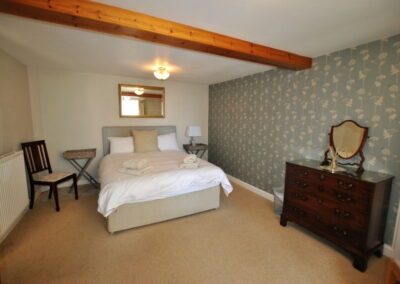 Bed beneath mirror. Chest of drawers with mirror against wall near bottom of bed.