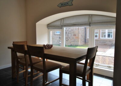 Dining table with six chairs in front of large window at floor-level