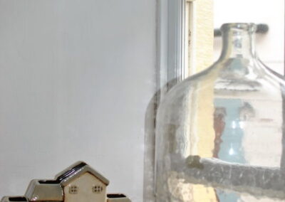 Windowledge with model of houses and large jar of seaglass