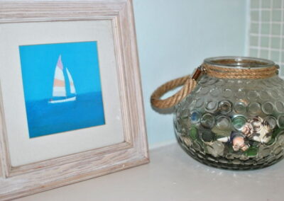 Picture of boat next to glass jar of beach finds