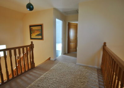 Wide landing with large rug. Doors leading to bathroom and bedroom.
