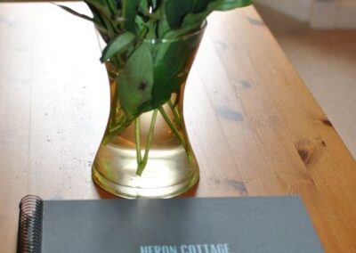 Heron Cottage guest book on coffee table with vase of pink flowers