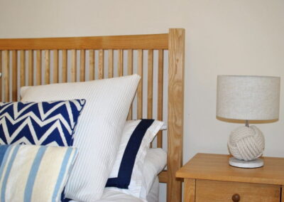 Close-up of bed with plenty of cushions and knot-design lamp on bedside table