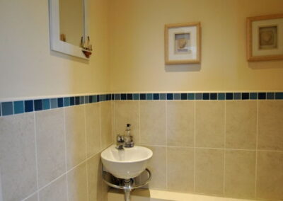 Cream tiled floor and half-tiled wall, with corner sink