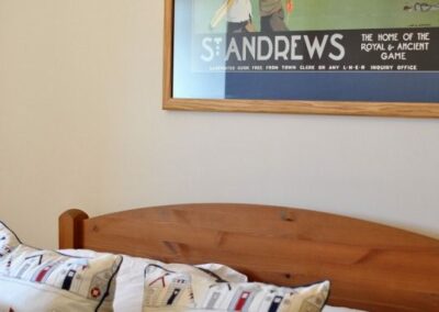 Close up of double bed with pillows and St Andrews poster on wall