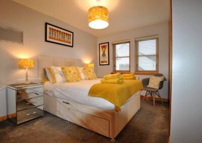 Large bedroom with white and yellow or golden linen and accessories
