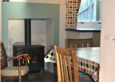 View of the wood burner and fire place beyond a table and chairs