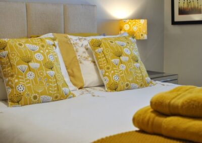 Detail of yellow and white cushions on bed