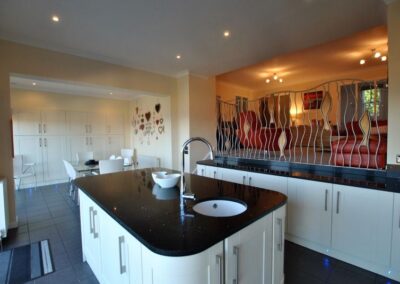Large kitchen island with sink. To the right a mezzanine floor with the lounge