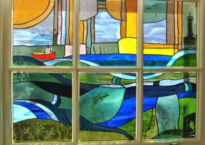 Stained glass window shows a harbour and sea scene with a boat