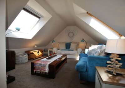 Lounge beneath sloped roof, two Velux windows let in a lot of light