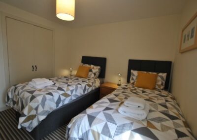 Two single beds with bedside tables and lamps next to each