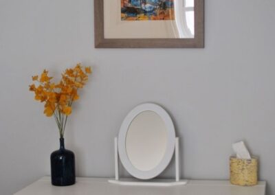 Mirror on dressing table beneath painting on wall