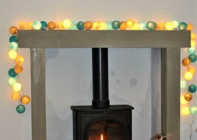 Wood-burning stove surrounded by lights on the mantelpiece
