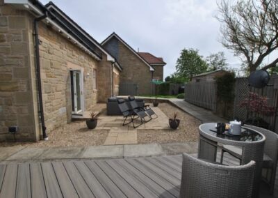The garden has several areas including a large lawn, decked area, barbecue and furnished summer house
