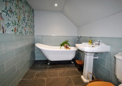 Bathroom tiled halfway up wall with white bathroom fittings