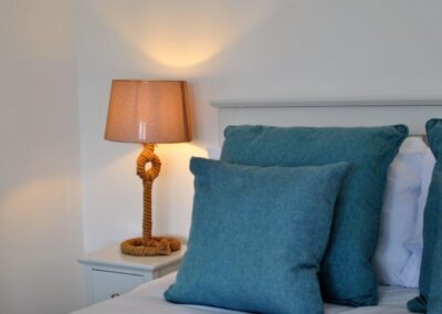 Turquoise cushions on bed next to bedside lamp made from rope