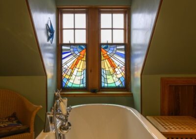 Colourful stained glass window above rolltop bath